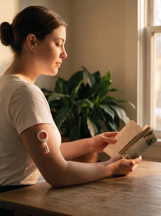 A woman reading while the Tasso device collects on her upper arm